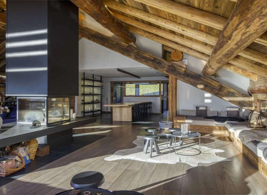 Experience luxury living in this stunning chalet, featuring a spacious open-plan design with exposed wooden beams and a cozy fireplace.