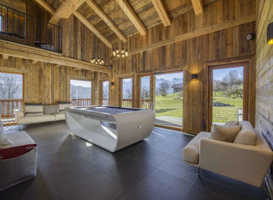 Experience luxury living in this stunning chalet, featuring a modern pool table and expansive windows that frame breathtaking mountain views.