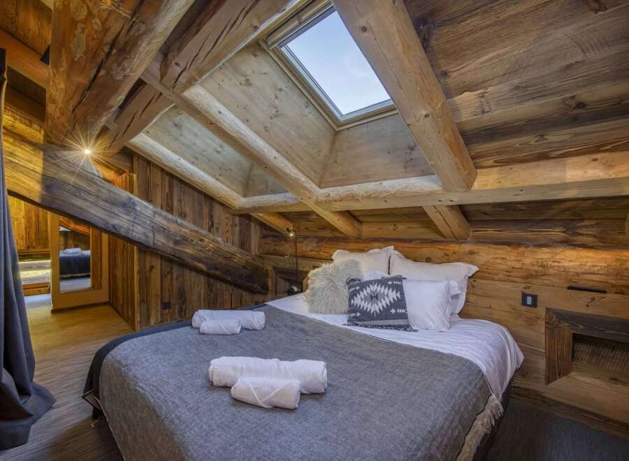 Experience rustic charm in this stunning bedroom featuring exposed wooden beams and a cozy ambiance.