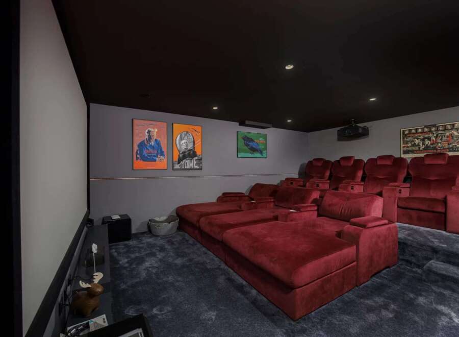 Step into luxury with this stunning home theater! Featuring plush red seating, a large screen, and a state-of-the-art projector, this space is perfect for movie nights.