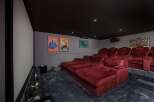 Step into luxury with this stunning home theater! Featuring plush red seating, a large screen, and a state-of-the-art projector, this space is perfect for movie nights.
