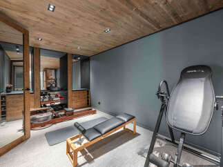 This luxurious home gym boasts a stunning wooden ceiling and modern gray walls, creating a sophisticated workout space.