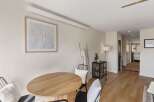 This inviting dining area features a stylish round wooden table, perfect for intimate gatherings.