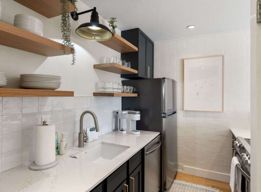 This stunning kitchen boasts modern design with sleek black cabinetry and elegant floating shelves.