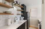 This stunning kitchen boasts modern design with sleek black cabinetry and elegant floating shelves.
