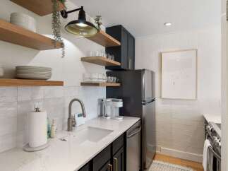 This stunning kitchen boasts modern design with sleek black cabinetry and elegant floating shelves.