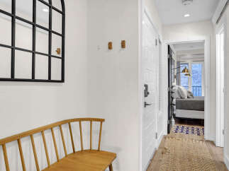 Step into this inviting entryway, showcasing a stylish bench and a decorative mirror.