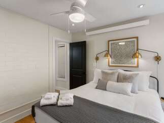 Step into this inviting bedroom, featuring a comfortable bed adorned with plush pillows and a stylish gray throw.