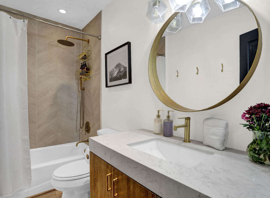 Step into luxury with this stunning bathroom! Featuring a sleek marble countertop, gold fixtures, and a modern design, this space offers both style and functionality.