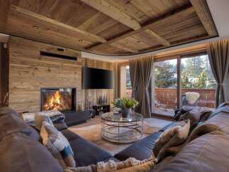 Experience the epitome of luxury living in this stunning chalet, featuring a cozy fireplace and a spacious, comfortable sofa.