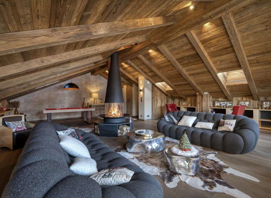 Experience luxury living in this stunning chalet, featuring a cozy living room with a unique fireplace and plush seating.