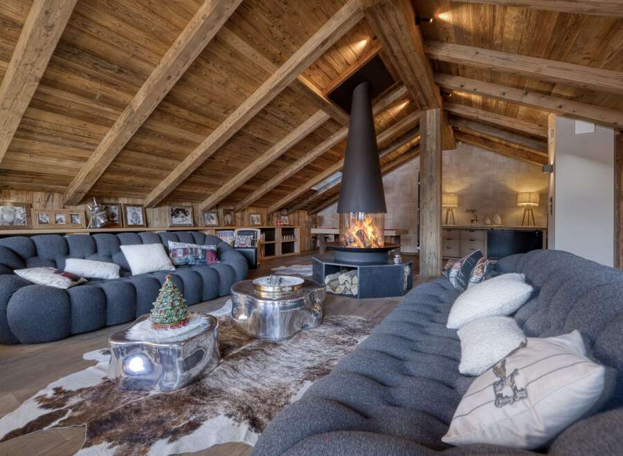 Experience luxury living in this stunning chalet, featuring a cozy living room with a unique fireplace and plush seating.