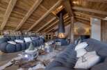 Experience luxury living in this stunning chalet, featuring a cozy living room with a unique fireplace and plush seating.