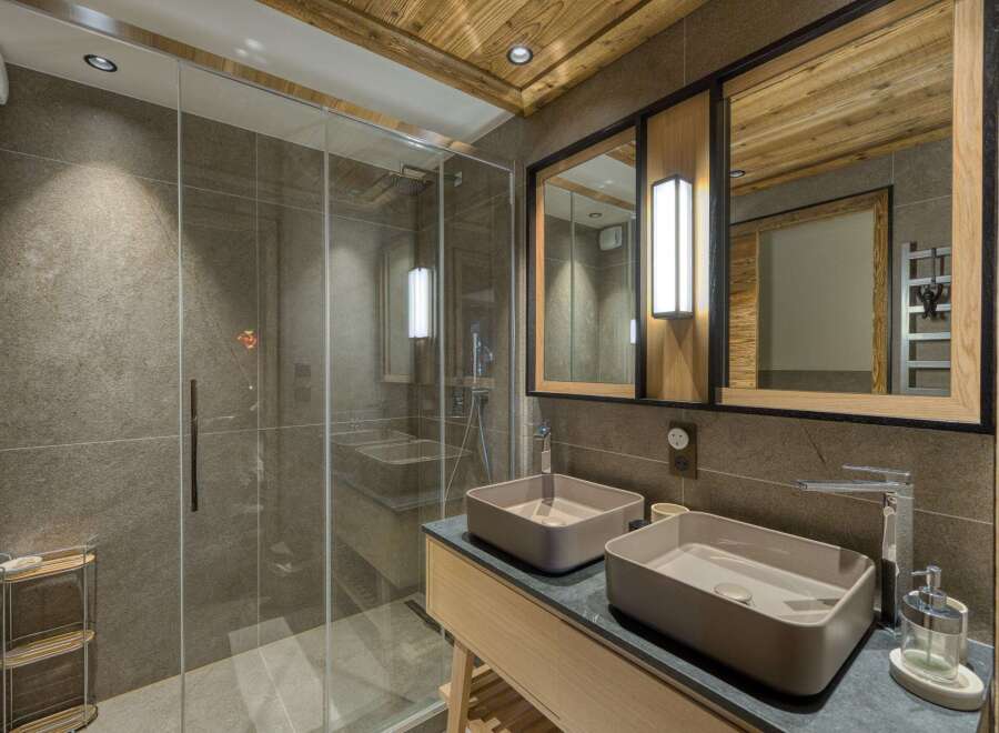 Step into luxury with this stunning bathroom, featuring a sleek glass shower and modern double sinks.
