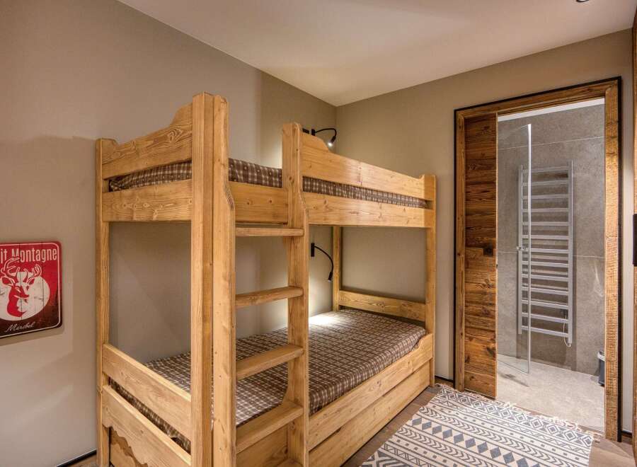 This cozy bedroom features custom-built wooden bunk beds, perfect for accommodating guests or family members.