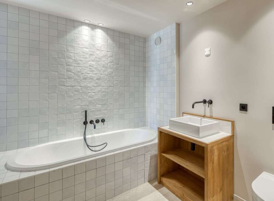 This modern bathroom features a sleek design with a soaking tub and a stylish vanity.