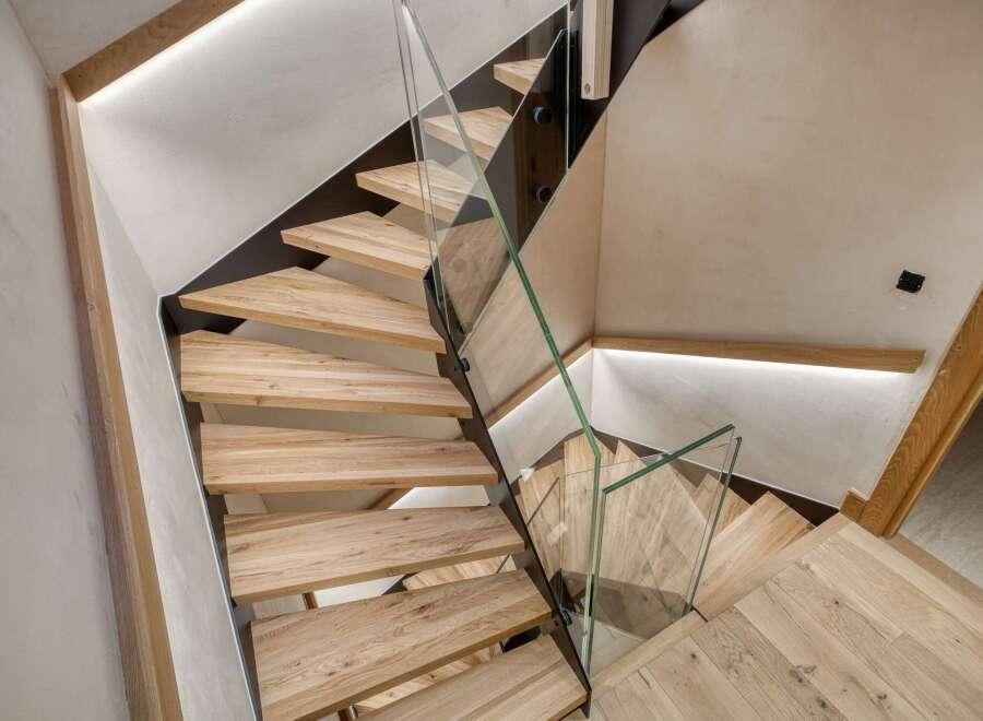 This stunning staircase is a true architectural marvel, featuring sleek glass railings and warm wooden steps.