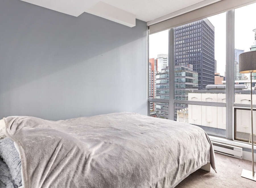 This stunning bedroom offers breathtaking city views through expansive windows, creating a bright and airy atmosphere.