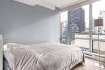 This stunning bedroom offers breathtaking city views through expansive windows, creating a bright and airy atmosphere.