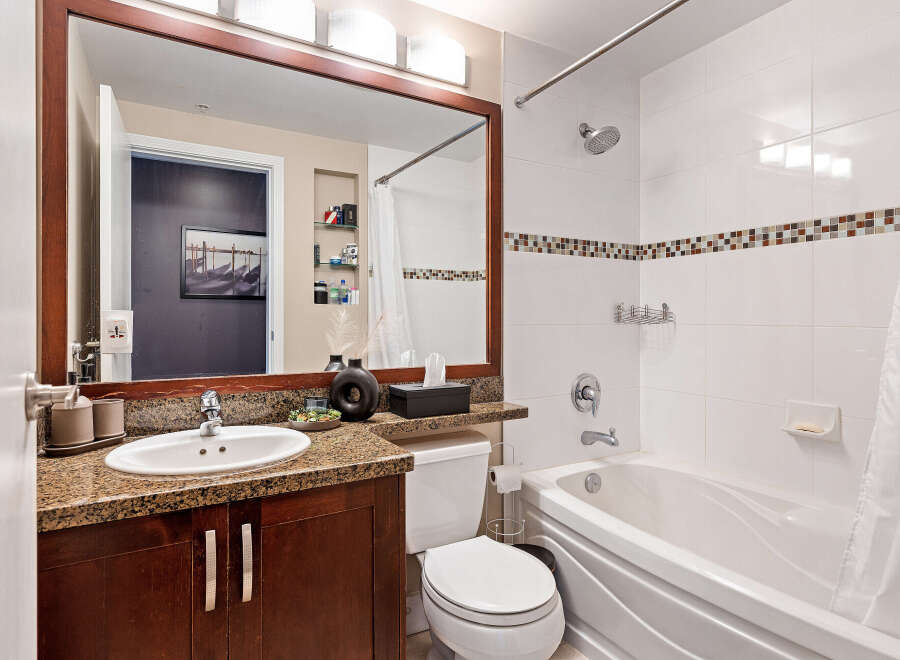 Step into this beautifully designed bathroom, featuring a sleek vanity with a granite countertop and a large mirror.