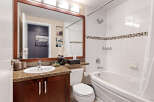 Step into this beautifully designed bathroom, featuring a sleek vanity with a granite countertop and a large mirror.