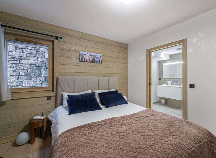 Experience the charm of this cozy bedroom featuring a rustic wooden accent wall and a comfortable bed with plush pillows.