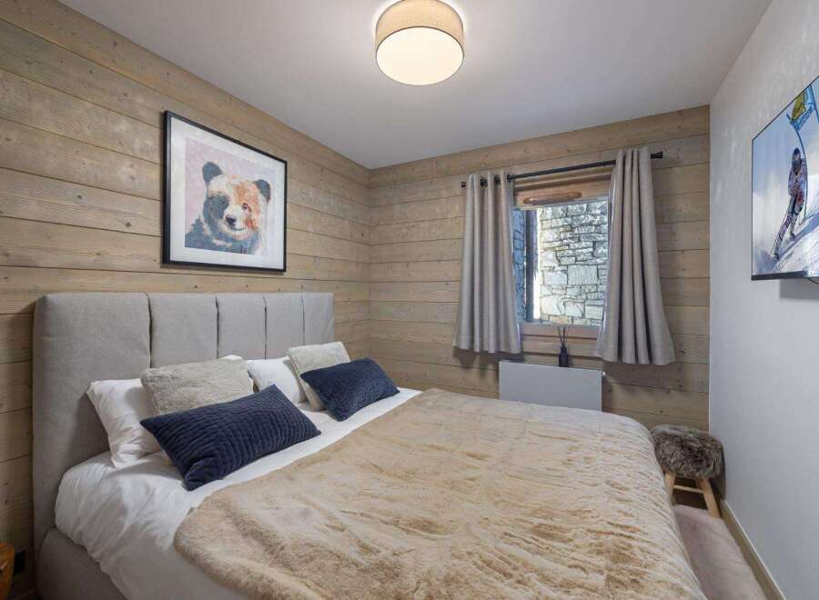 Experience the ultimate comfort in this cozy bedroom, featuring a plush bed and a charming bear artwork.