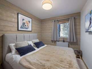 Experience the ultimate comfort in this cozy bedroom, featuring a plush bed and a charming bear artwork.