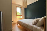 This cozy bedroom features a modern design with a dark accent wall and a light-colored wooden bed frame.