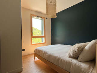 This cozy bedroom features a modern design with a dark accent wall and a light-colored wooden bed frame.