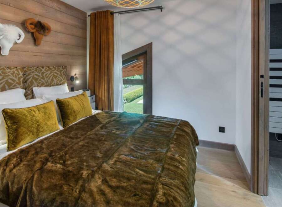 Experience luxury in this stunning bedroom featuring a cozy bed adorned with plush pillows and a warm, inviting blanket.