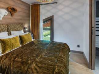 Experience luxury in this stunning bedroom featuring a cozy bed adorned with plush pillows and a warm, inviting blanket.