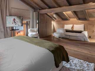 Experience luxury living in this stunning property, featuring a cozy bedroom with a plush bed and a stylish seating area.