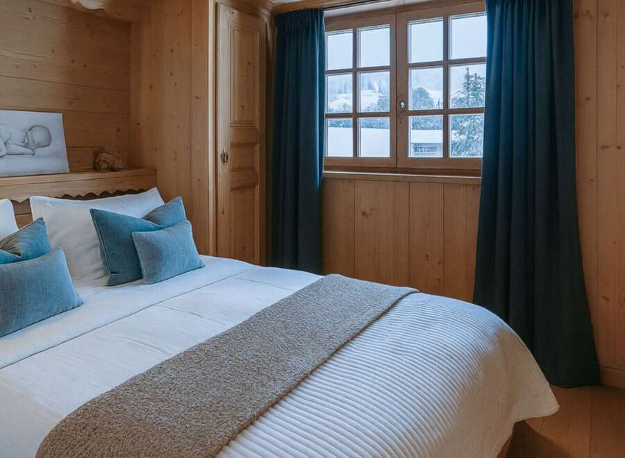 Experience the charm of this cozy bedroom, featuring warm wooden paneling and a comfortable bed.