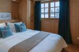 Experience the charm of this cozy bedroom, featuring warm wooden paneling and a comfortable bed.