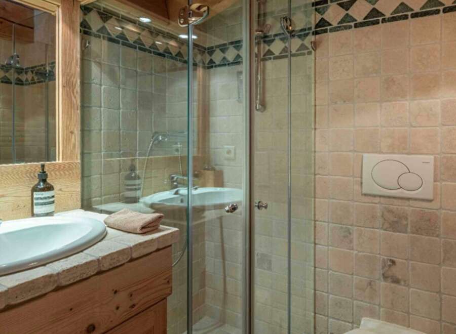 This charming bathroom features a glass-enclosed shower, a stylish sink, and a wooden vanity.