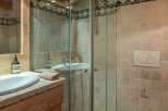 This charming bathroom features a glass-enclosed shower, a stylish sink, and a wooden vanity.