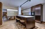 This modern kitchen boasts sleek, dark cabinetry and a stunning marble countertop, perfect for both cooking and entertaining.