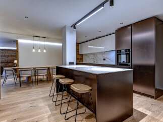This modern kitchen boasts sleek, dark cabinetry and a stunning marble countertop, perfect for both cooking and entertaining.
