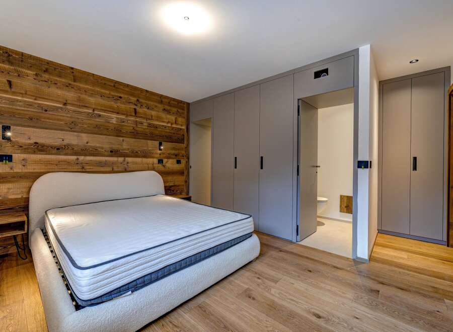 Experience luxury in this stunning bedroom featuring a unique wooden accent wall and a plush, inviting bed.