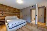 Experience luxury in this stunning bedroom featuring a unique wooden accent wall and a plush, inviting bed.