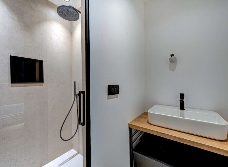 This modern bathroom features a sleek shower with a rainfall showerhead and a stylish sink.