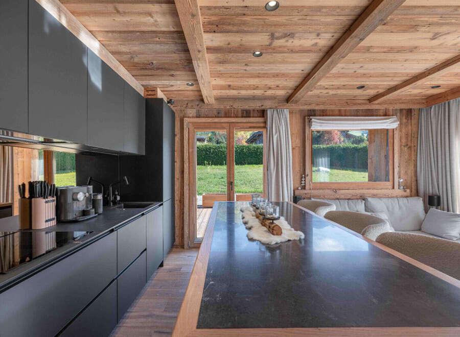 This stunning kitchen boasts a modern design with sleek black cabinetry and a contrasting wooden ceiling, creating a warm and inviting atmosphere.