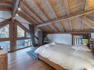 Experience the charm of this stunning bedroom with its rustic wooden beams and natural light.