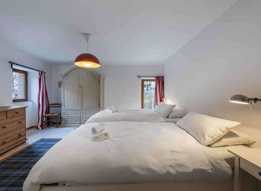 This charming bedroom features two comfortable beds with crisp white linens, perfect for a relaxing stay.