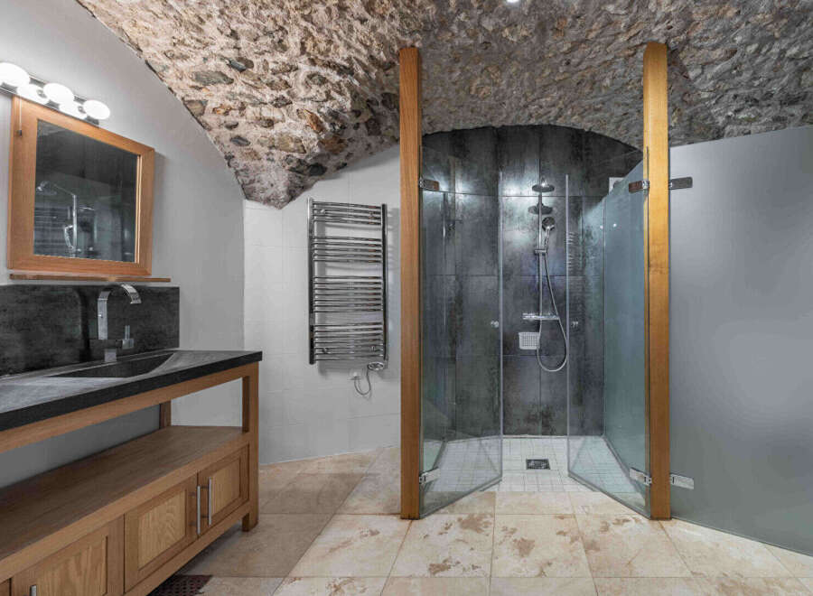 Step into luxury with this stunning bathroom featuring a unique stone ceiling and a modern shower.