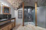 Step into luxury with this stunning bathroom featuring a unique stone ceiling and a modern shower.
