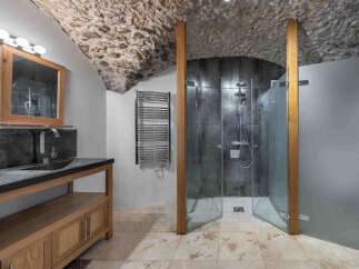 Step into luxury with this stunning bathroom featuring a unique stone ceiling and a modern shower.