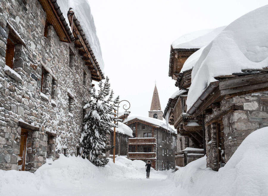 Explore the charm of this snow-covered village, featuring stone-built houses and a picturesque church steeple.