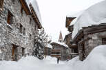 Explore the charm of this snow-covered village, featuring stone-built houses and a picturesque church steeple.